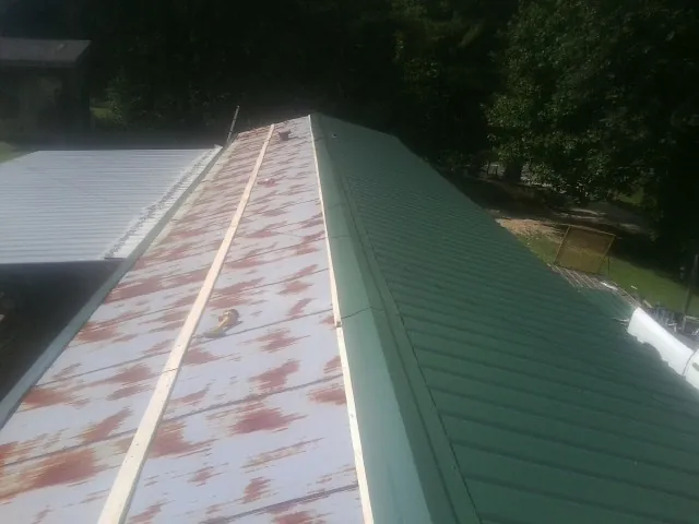 Old rusted panels beside newly installed green metal roofing — Wind Damage Roof Repair by Roofing Brothers in Brookwood