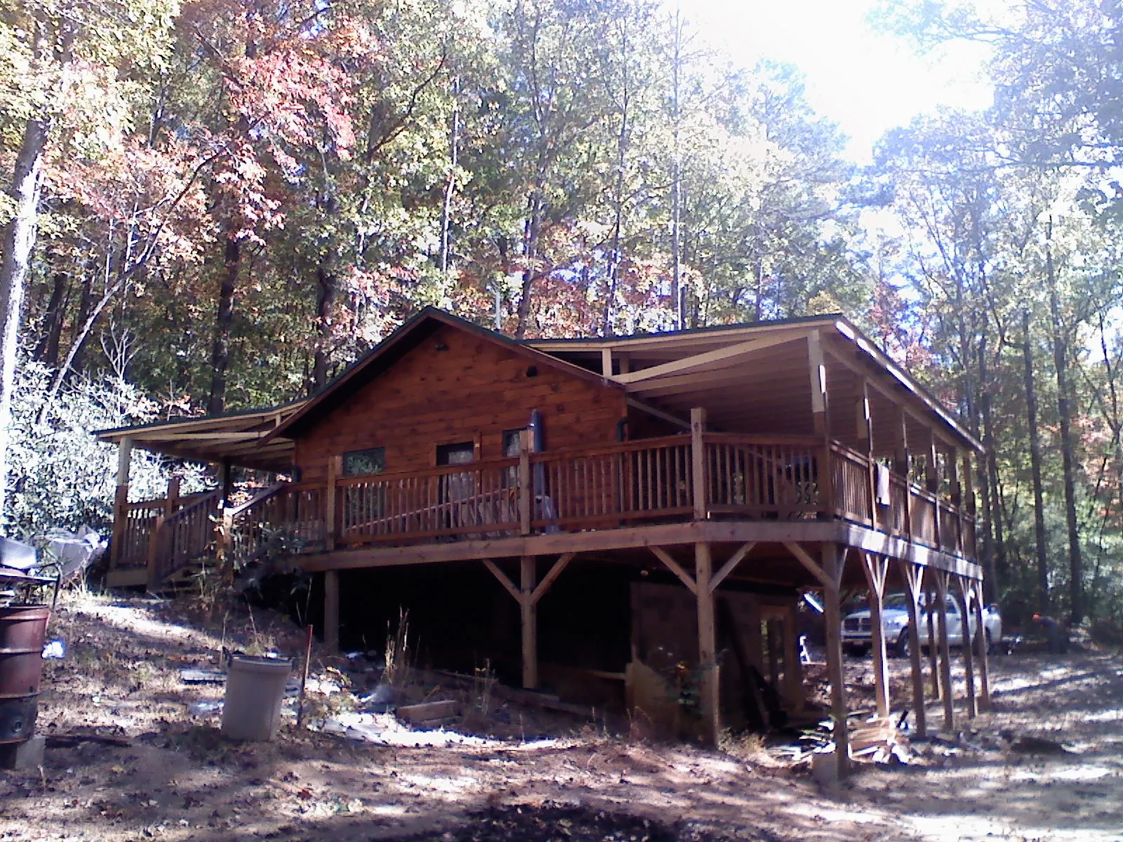 Log cabin with a wraparound porch and metal roof in the fall in Brookwood