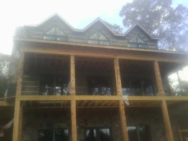 Dormers and porch framing on a large log home under construction — Roof Coating work by our crew in Brookwood