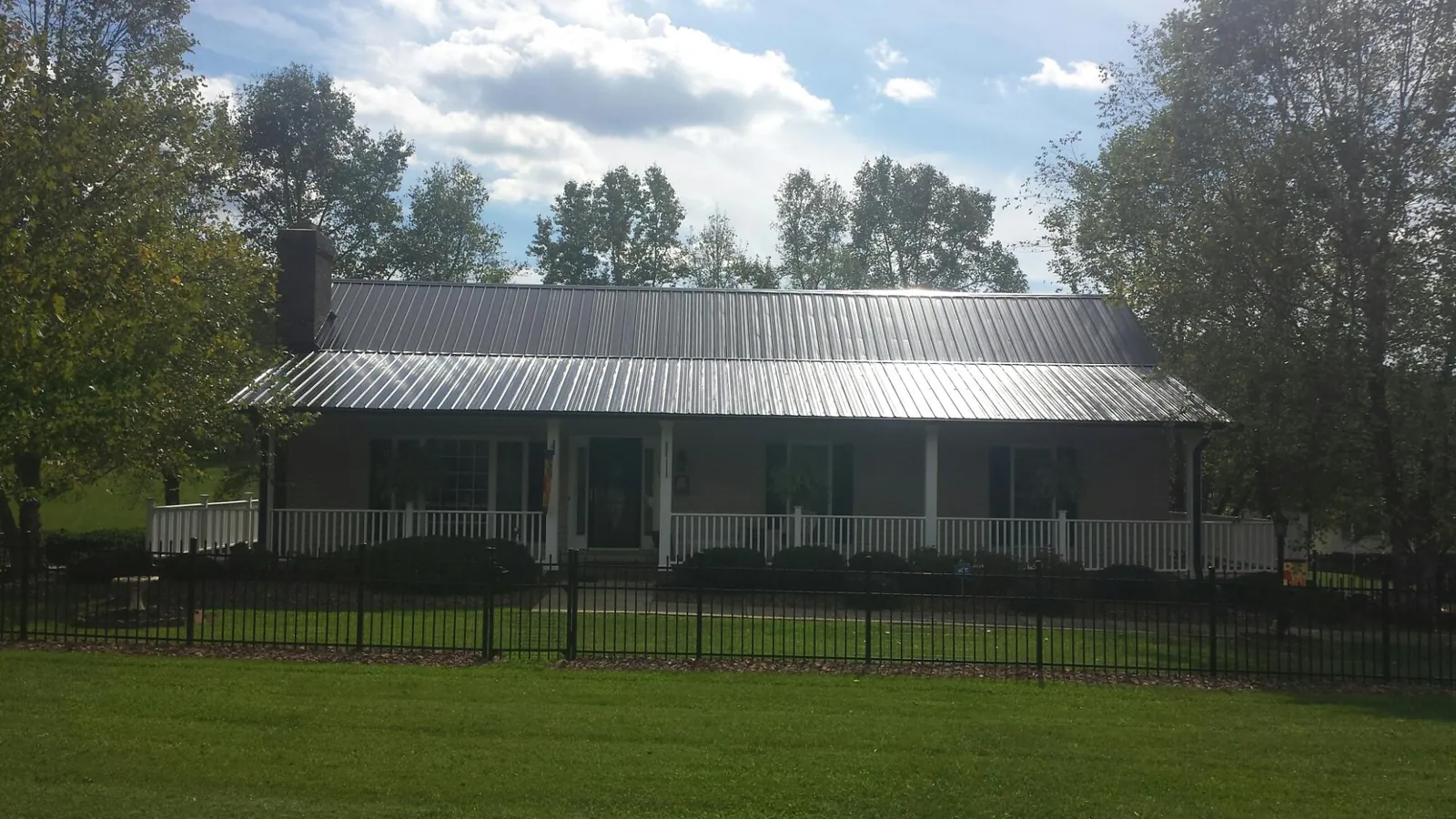 Gray metal roof on a brick ranch with a full width front porch — Gutter Guard Installation work by our crew in Brookwood