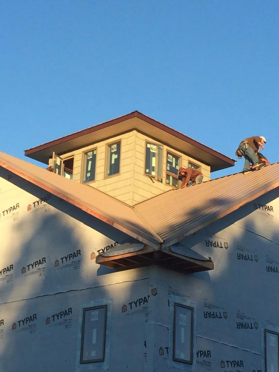 Roofers working around a rooftop cupola on a new metal roof at sunset — Roof Waterproofing in Brookwood by Roofing Brothers